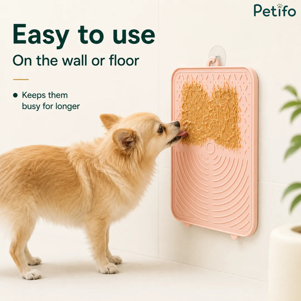 Cute dog licking peanut butter off a wall-mounted pink Petifo slow feeder lick mat